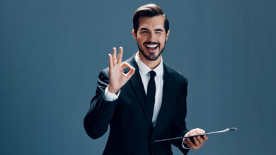 Portrait of a business man in a stylish suit smile with teeth with a tie beautiful face on a blue isolated background with a tablet in his hands. Business concept young businessman startup copy place. High quality photo