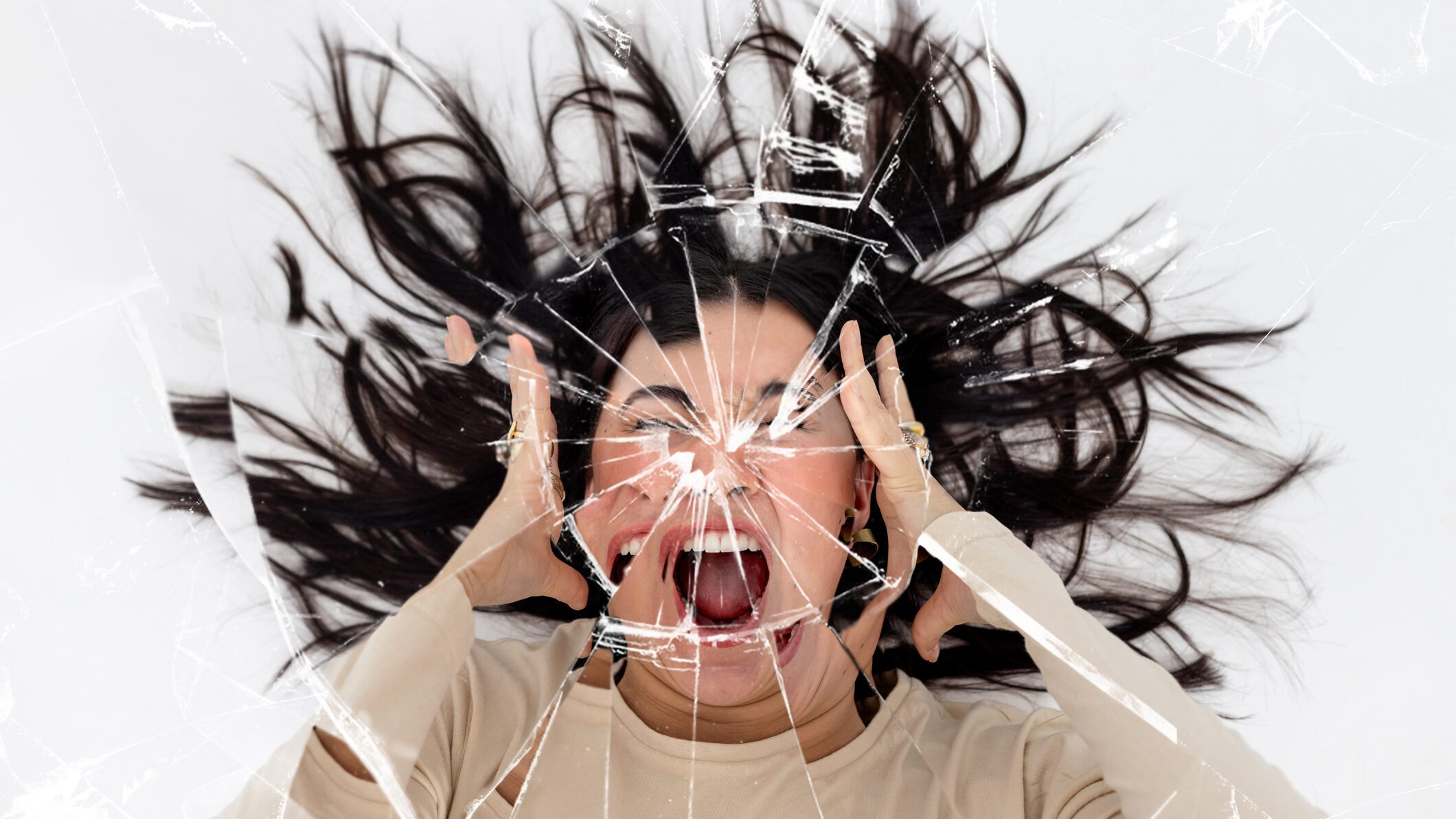 Woman screaming with her hands either side of her head with a cracked mirror effect over the image.