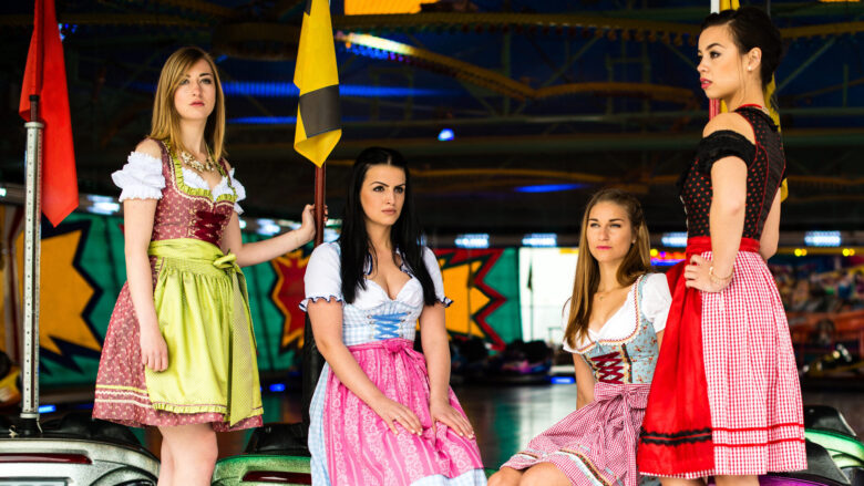 Ein Foto zeigt vier junge Frauen in Dirndln am Rand eines Autoscooters.