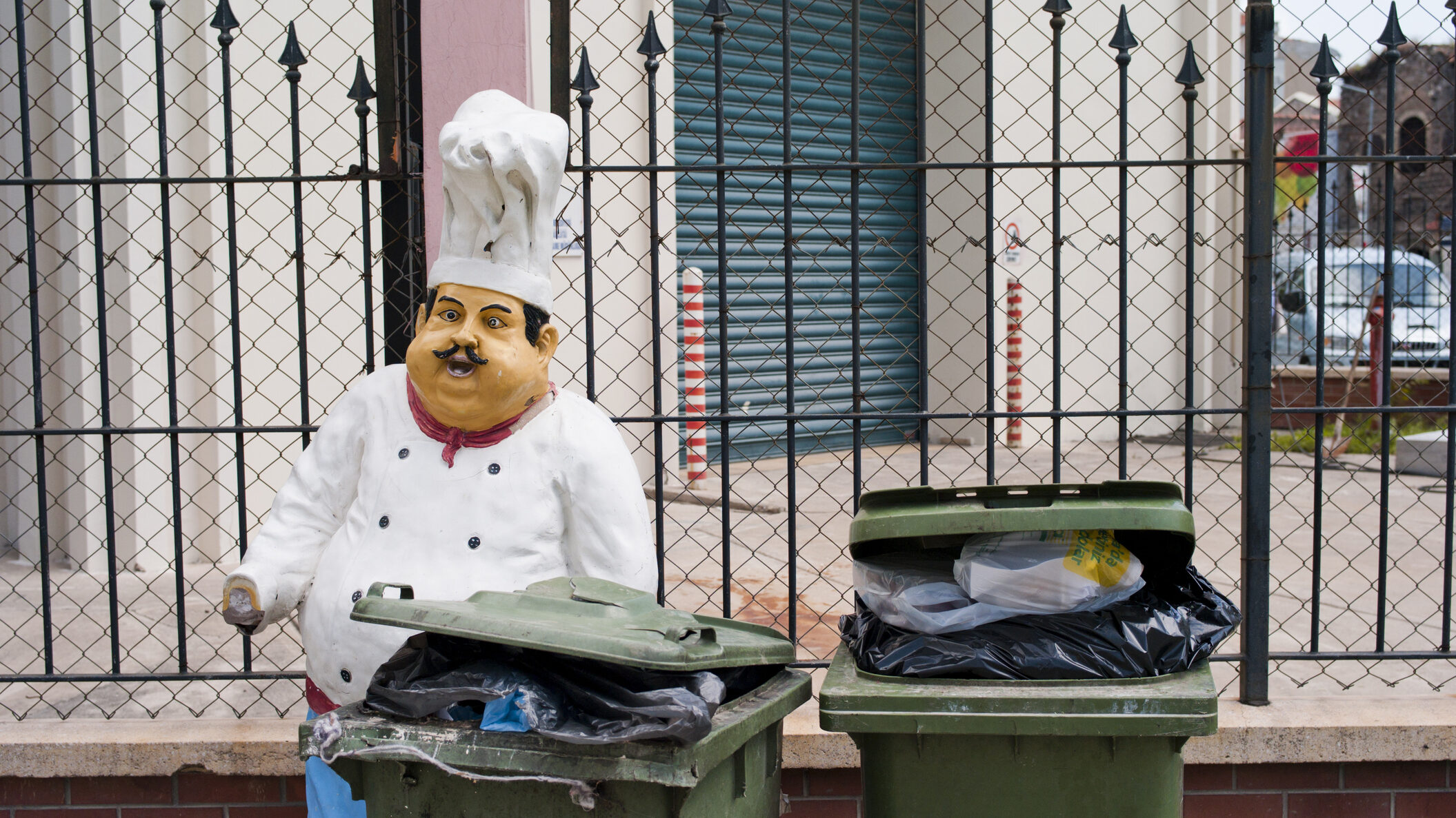 "Izmir, Turkey - April 20, 2012: A broken chef sculpture and other kind of wastes in the garbage bin in the street in Konak district."