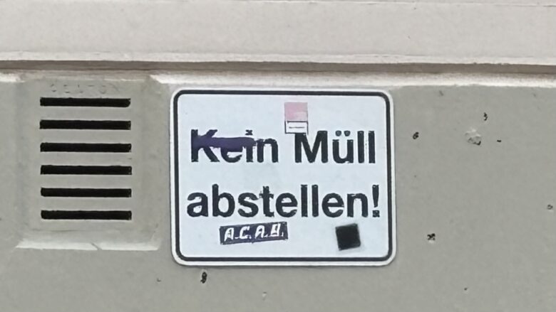 Schild mit der Aufschrift "Kein Müll abstellen!" mit Stickern und Schmierereien