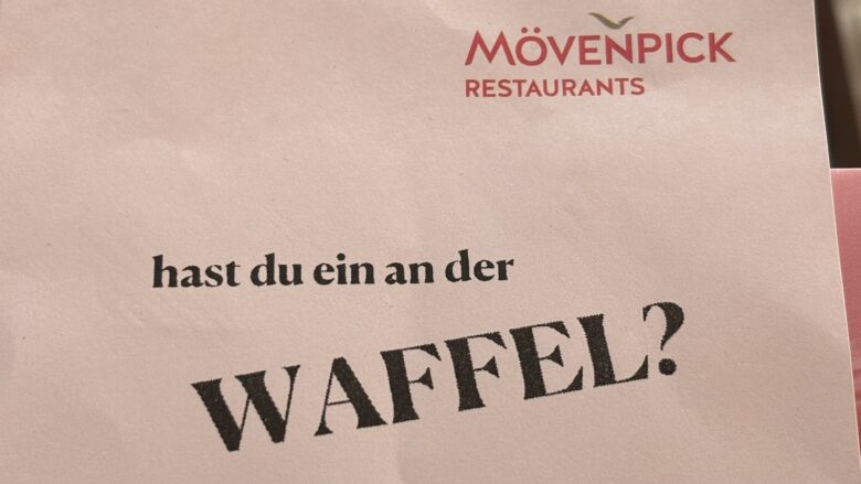 Detail einer Speisekarte von "Mövenpick Restaurants" mit dem Text "hast du ein an der Waffel?"