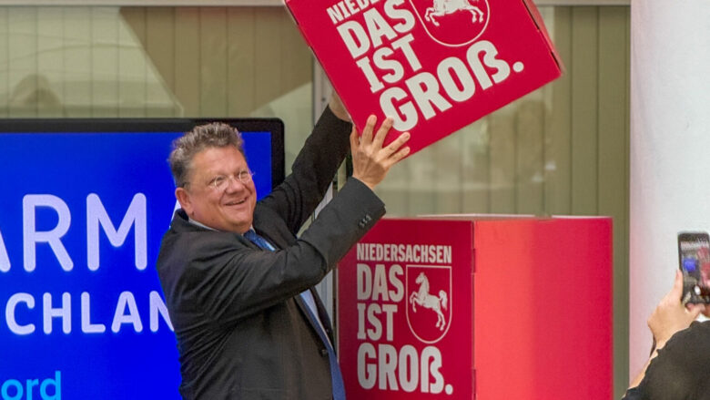 Andreas Philippi stapelt einen übermannshohen Turm aus Pappkartons mit der Aufschrift "Niedersachsen ist groß".