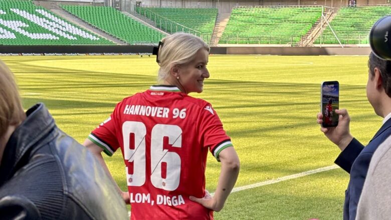Eine blonde Frau in einem Hannover 96-Trikot mit dem Schriftzug "Shalom Digga".